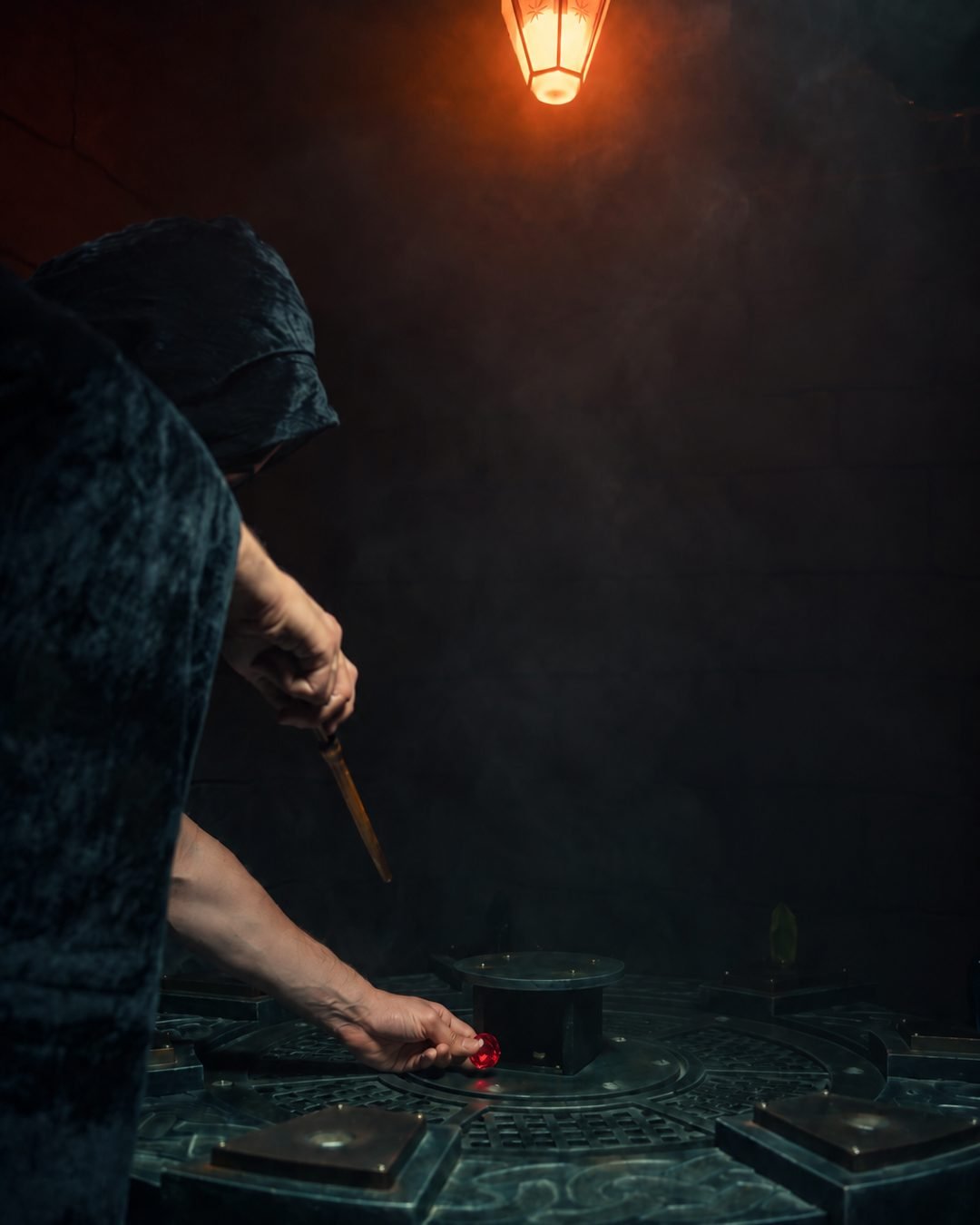 Un sorcier encapuchonné pose une pierre rouge sur une table d'énigmes dans l'escape game sorcellerie à Lyon
